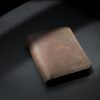 Brown full-grain leather bifold wallet on dark leather