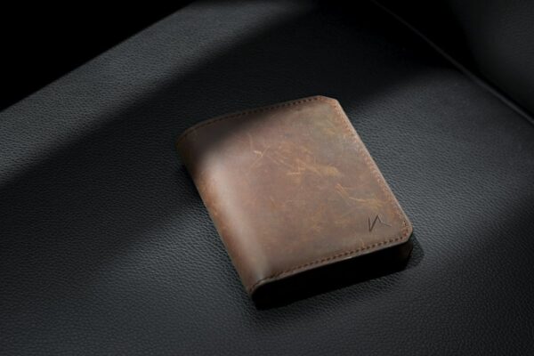 Brown full-grain leather bifold wallet on dark leather