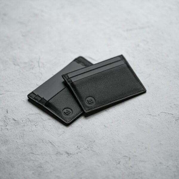 The Bifold Black leather bifold wallet on a pale surface