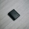 Black leather wallet on a wooden table