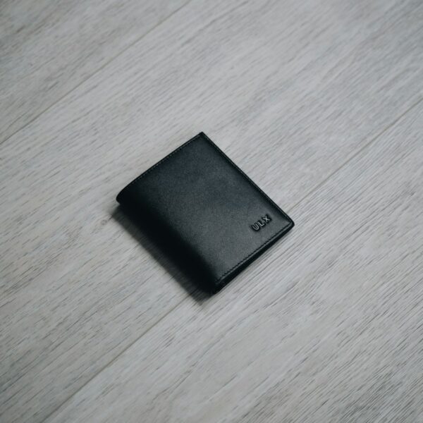 Black leather wallet on a wooden table
