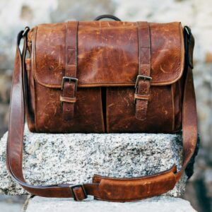 Brown leather satchel bag resting on a concrete surface
